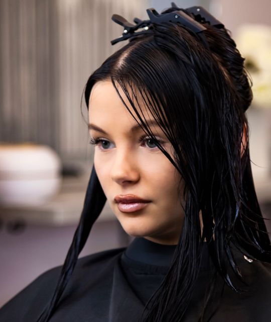 Hairstylist making fashionable hairstyle in hair salon. Portrait of brunette lady visit hairdresser Hairstylist making fashionable hairstyle in hair salon. Portrait of brunette lady visit hairdresser, sitting on barber chair, looking away. Customer service at hair salon, haircare. Copy ad text space